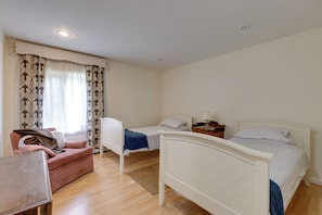 Een slaapkamer met twee eenpersoonsbedden, een slaapbank en een klein tafeltje.