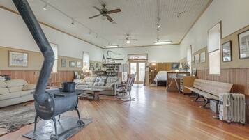 A spacious living room with a large fireplace, wooden flooring, and a cozy seating area.