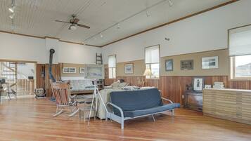 A spacious room with wooden floors, a bed, a rocking chair, and a desk with a lamp.