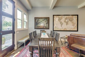 A dining area with a long wooden table, benches, and a world map on the wall.