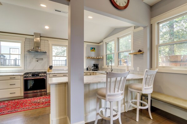 A modern kitchen with a central island, white cabinetry, and a red patterned rug.