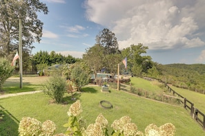 A grassy outdoor area with a wooden fence, a swing set, and a pool.