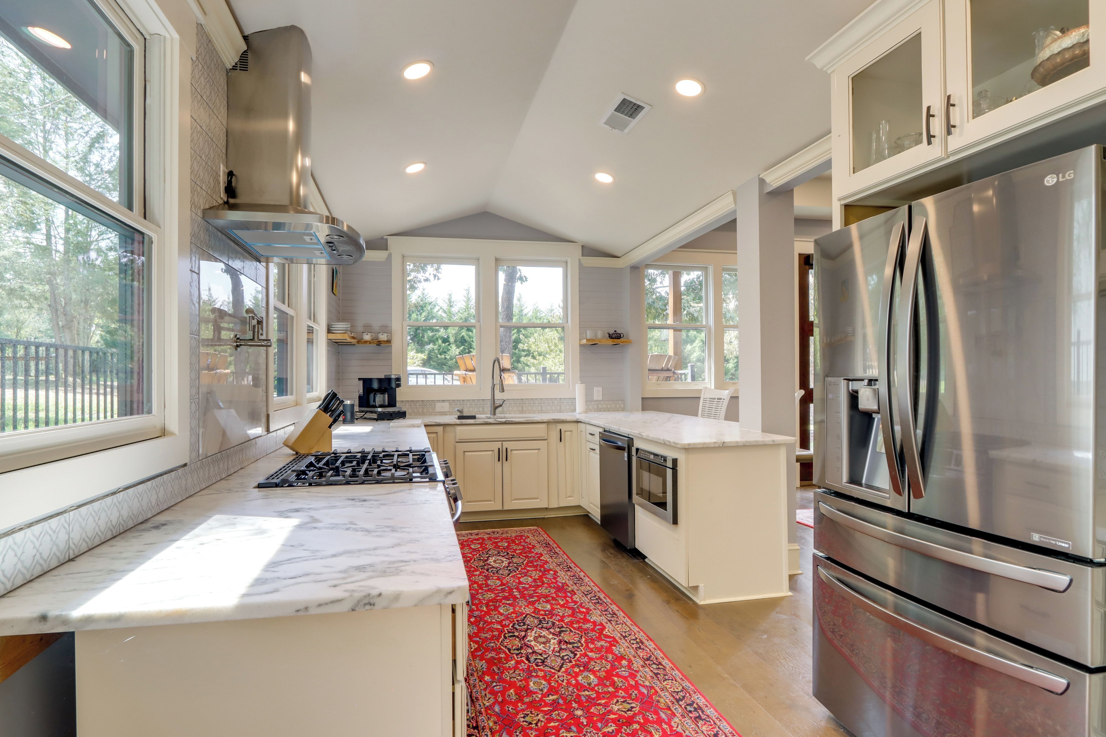 A modern kitchen with a central island, stainless steel appliances, and large windows.