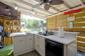 Una cocina con armarios blancos, lavavajillas integrado y encimera de madera.