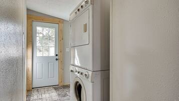 A laundry room with a front-loading washer and dryer, a wooden door, and a textured wall.
