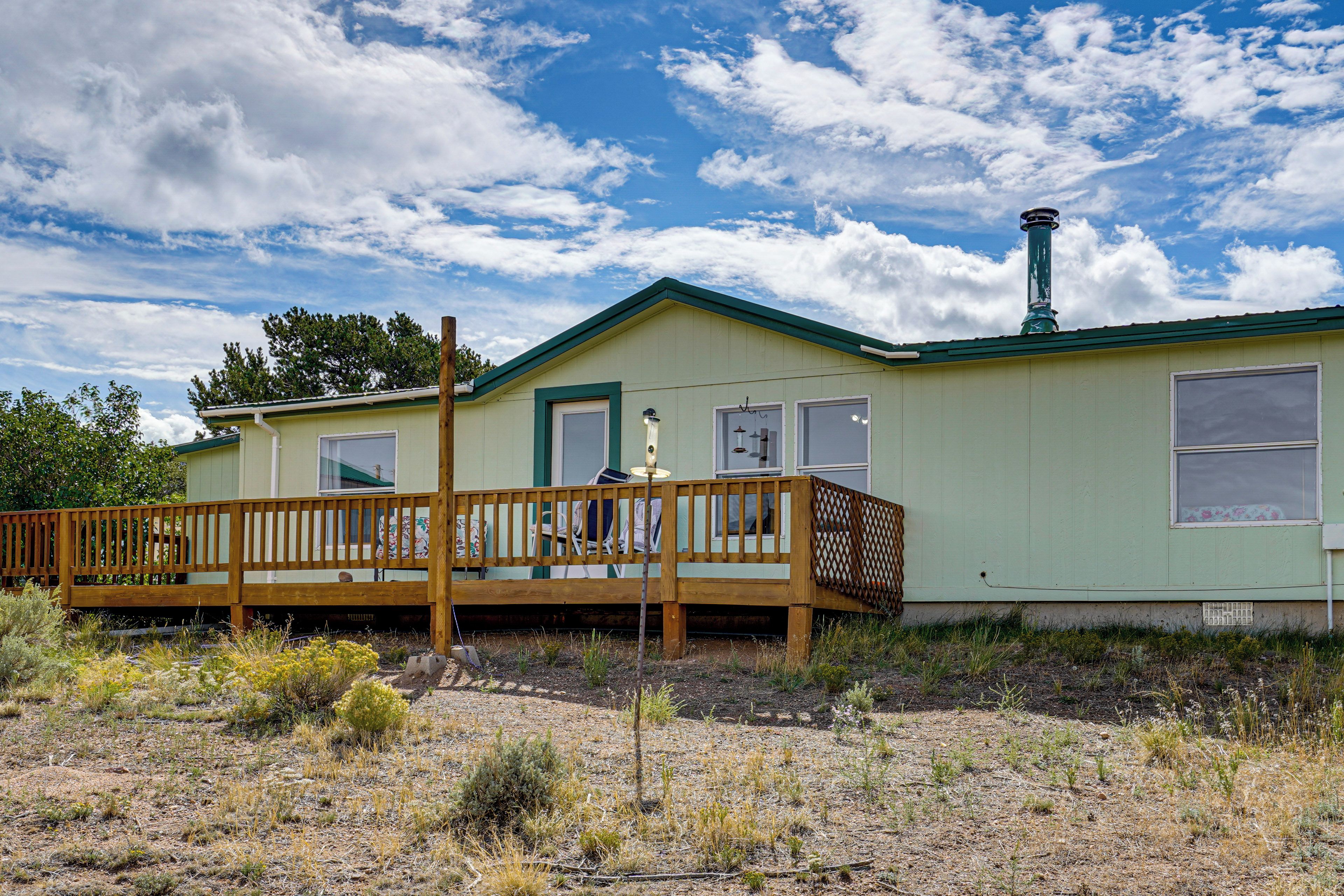 A single-story house with a green roof and a wooden deck.