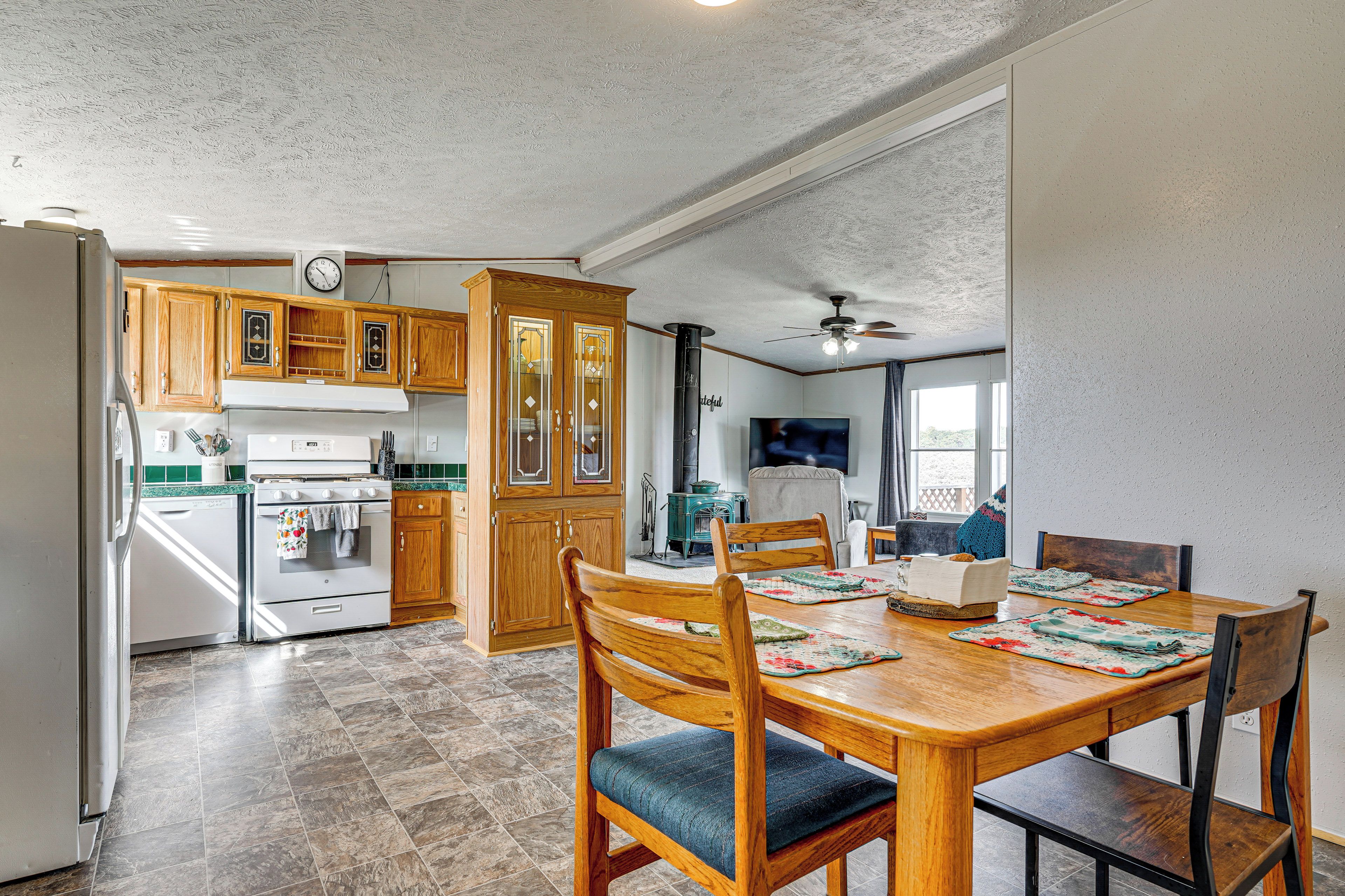 A kitchen with wooden cabinets, a stove, and a dining area with a table and chairs.