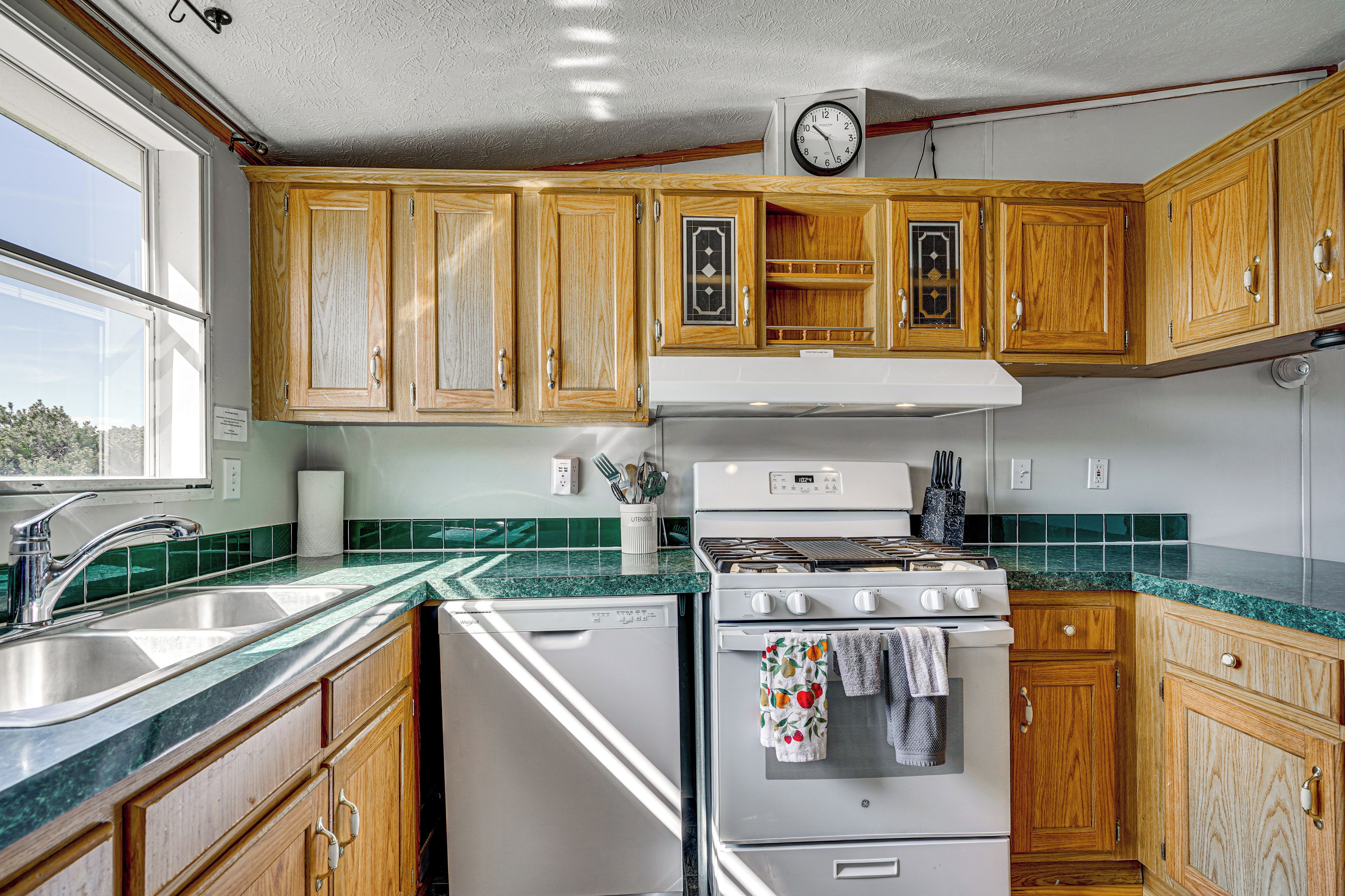 A kitchen with wooden cabinets, a white stove, and a green tiled backsplash.