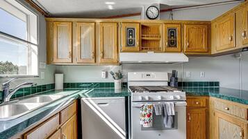A kitchen with wooden cabinets, a white stove, and a green tiled backsplash.