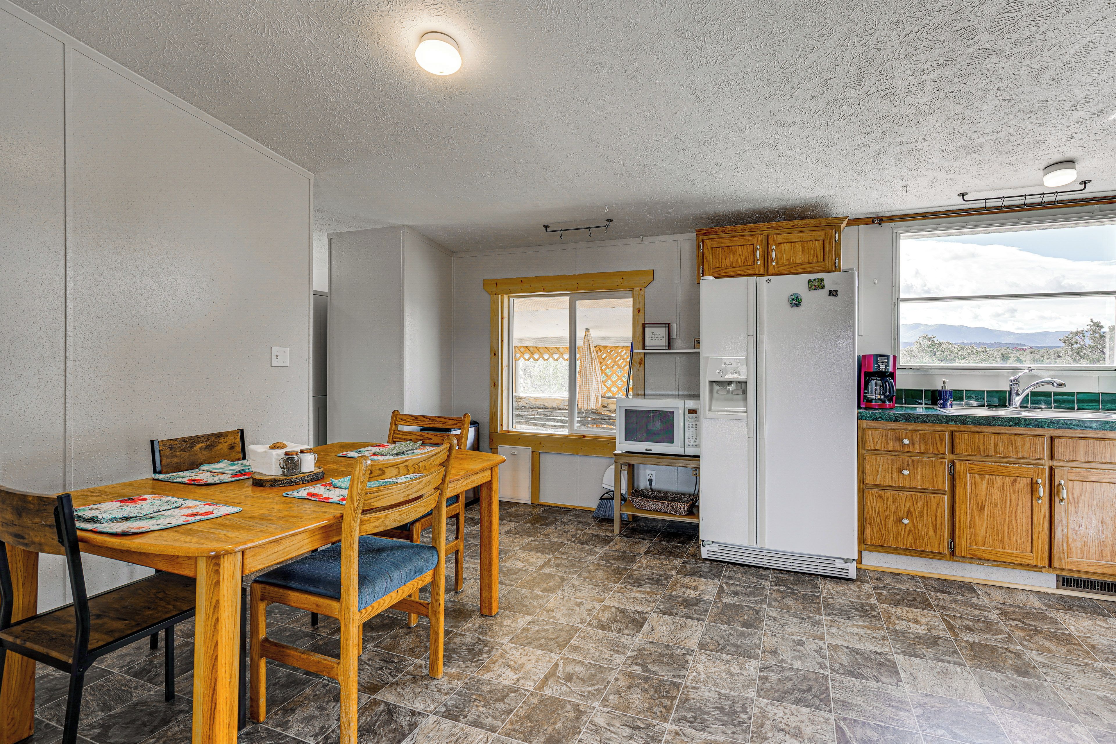 A compact kitchen with a dining area, wooden cabinets, a built-in microwave, and a window with a view.