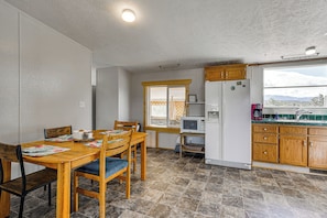 Una cocina compacta con zona de comedor, armarios de madera, microondas integrado y ventana con vistas.