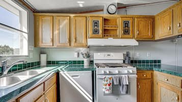 A kitchen with wooden cabinets, a white stove, and a green tiled backsplash.
