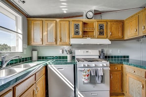 A kitchen with wooden cabinets, a white stove, and a green tiled backsplash.