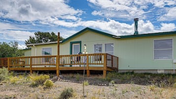 A single-story house with a green roof and a wooden deck.