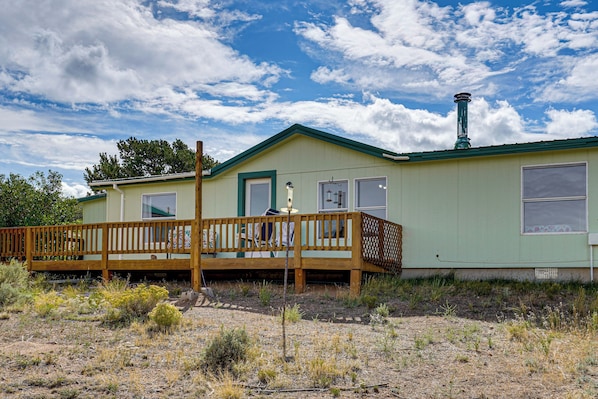 A single-story house with a green roof and a wooden deck.
