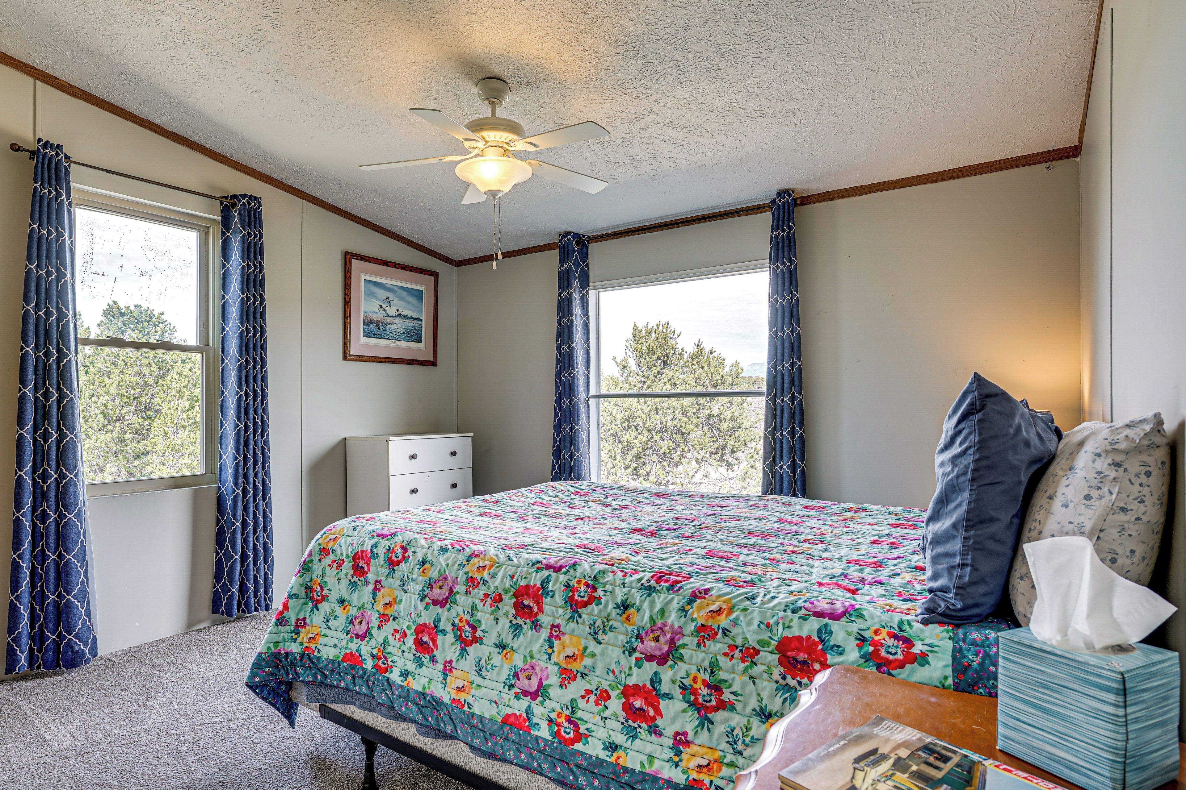 A bedroom with a bed, a nightstand, a dresser, and a ceiling fan.