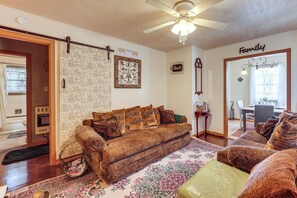 A living room with a brown sofa, a patterned rug, a ceiling fan, and a sign that reads 'HOME sweet HOME'. - Near Dtwn Jackson: Home w/ Screened Porch (Jackson)