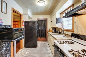 A compact kitchen with a refrigerator, stove, sink, and a window with blinds. - Near Dtwn Jackson: Home w/ Screened Porch (Jackson)