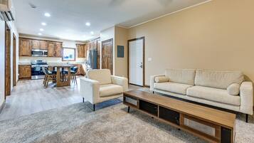 A spacious living room with a sofa, a coffee table, and a kitchen in the background.