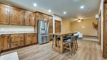A kitchen with wooden cabinets, a stainless steel refrigerator, and a dining area with a wooden table and chairs.