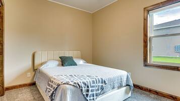 A bedroom with a bed, a window, and a view of a house.