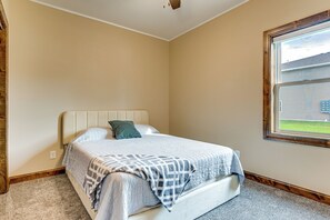 Un dormitorio con cama, ventana y vista a una casa.