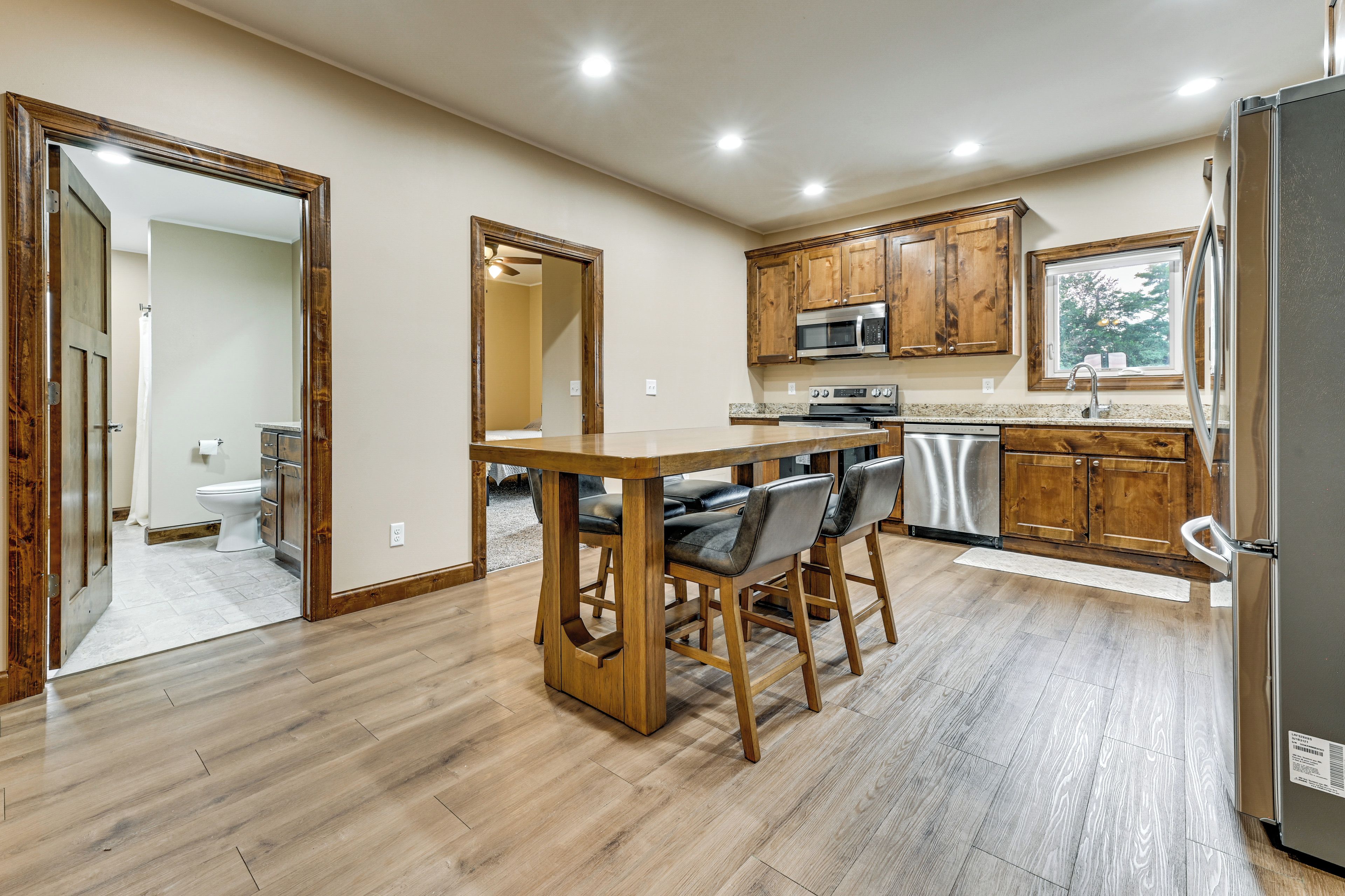 A kitchen with wooden cabinets, a stainless steel refrigerator, a microwave, and a sink.