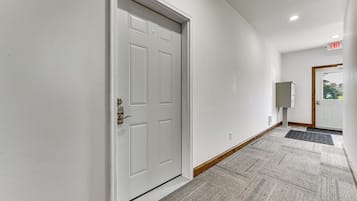 A hallway with a white door, a mailbox, and a doormat.