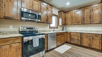 A kitchen with wooden cabinets, stainless steel appliances, granite countertops, and a tiled backsplash.