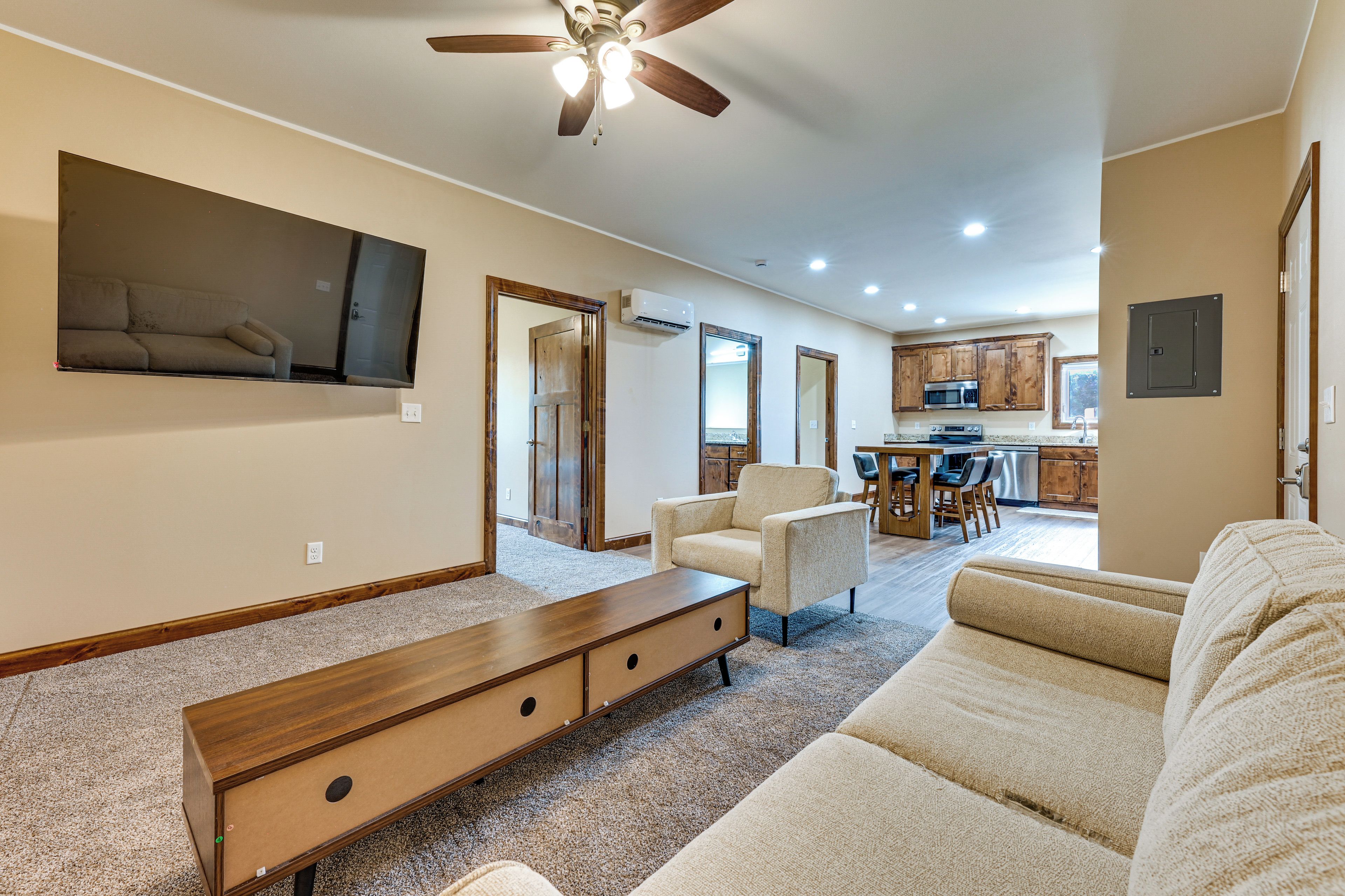 A spacious living room with a large sectional sofa, a wooden bench, and a ceiling fan.