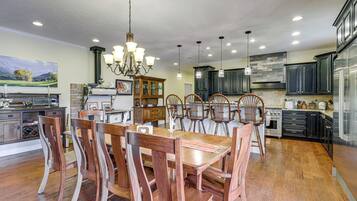 A spacious kitchen with wooden dining chairs, a chandelier, and modern appliances.