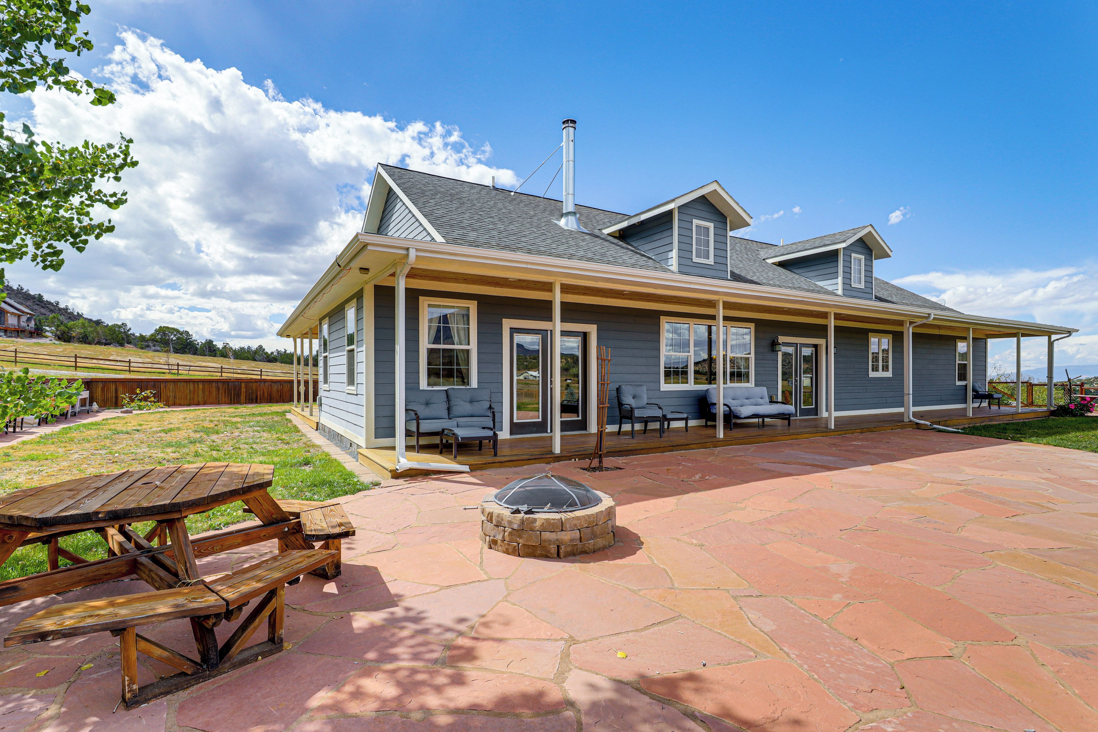A two-story house with a covered patio area, a fire pit, and a wooden deck.