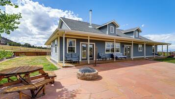 A two-story house with a covered patio area, a fire pit, and a wooden deck.