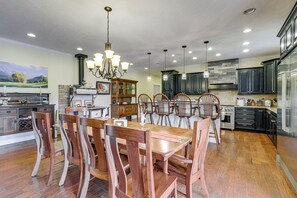 A spacious kitchen with wooden dining chairs, a chandelier, and modern appliances.