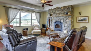 A living room with leather sofas, a stone fireplace, and a large window with curtains.
