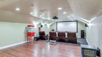 A home theater room with a large screen, reclining chairs, a popcorn cart, and a projector.