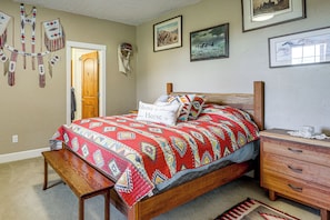 A bedroom with a wooden bed, a bench, a nightstand, and a dresser. There are wall hangings and framed pictures on the walls.