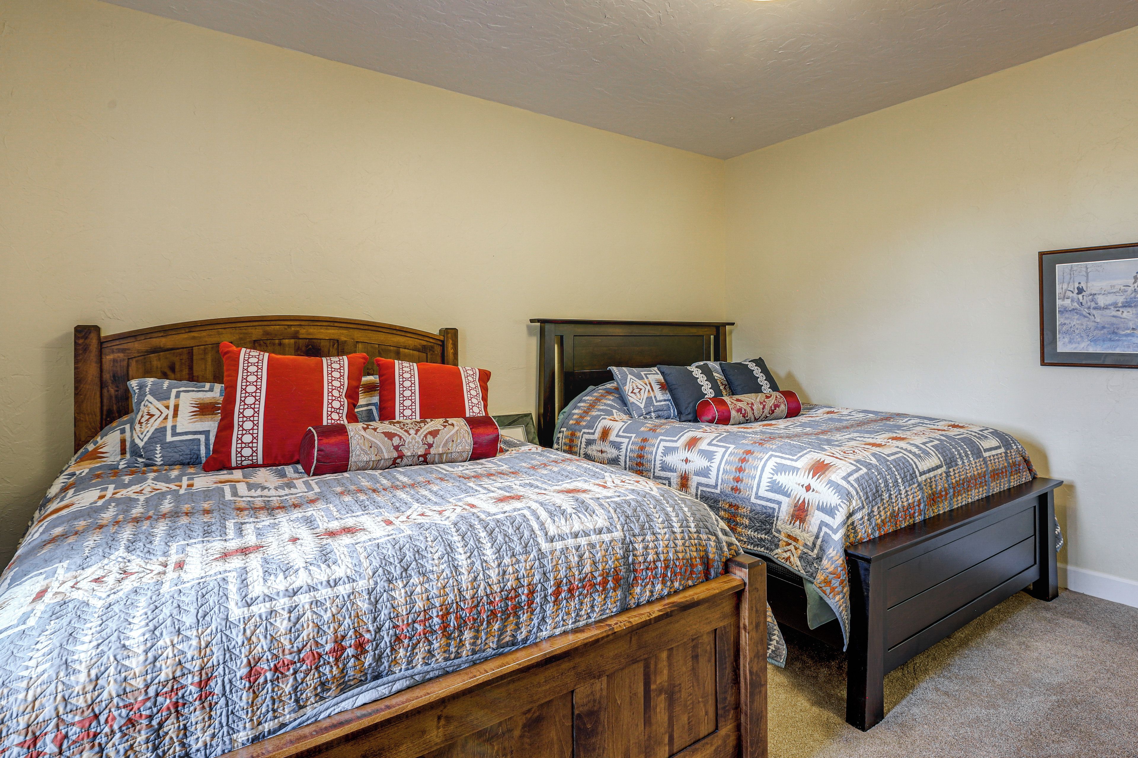 A bedroom with two wooden beds, each with patterned bedding and multiple pillows.