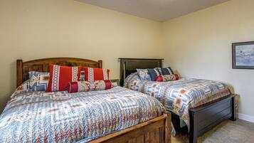 A bedroom with two wooden beds, each with patterned bedding and multiple pillows.