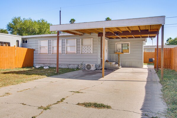 A single-story mobile home with a covered patio area, a fenced yard, and a concrete driveway. - Central Rio Grande Valley Hub w/ Full Kitchen! (La Feria)