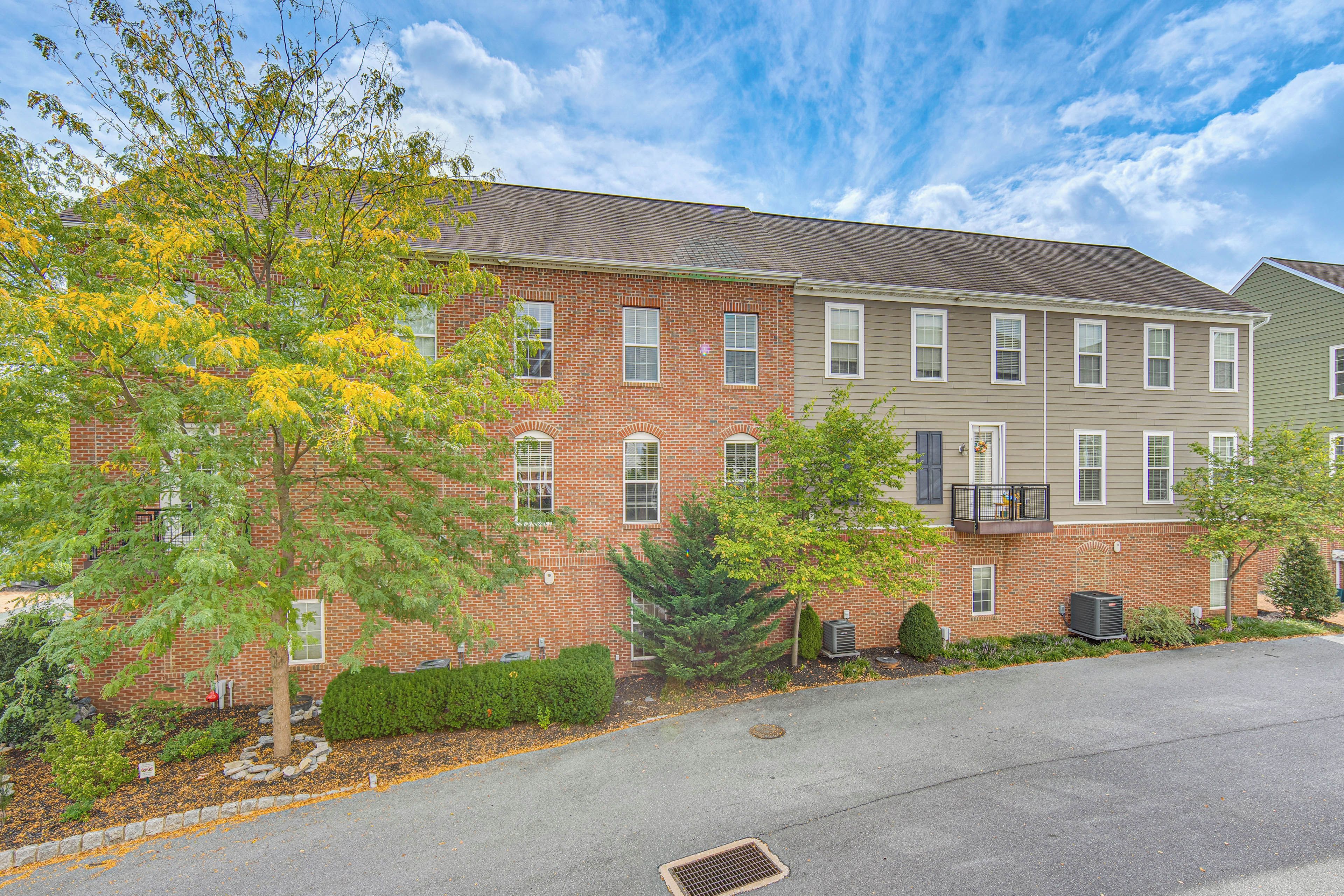 A multi-story brick building with a flat roof, a small balcony, and a well-maintained lawn.