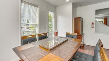 A dining area with a long wooden table, cushioned chairs, and a glass vase centerpiece.