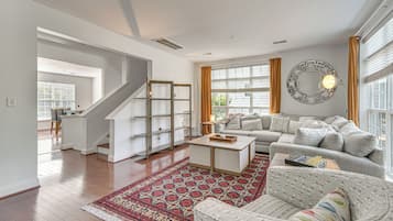 A spacious living room with a staircase, a sofa set, a coffee table, and a patterned rug.