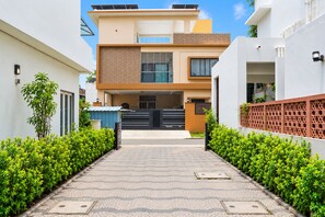 Une maison moderne à deux étages, dotée d’une allée pavée, d’un garage et d’une entrée fermée par un portail.
