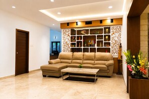 A living room with a sectional sofa, a coffee table, and a decorative wall unit. - Kingsley by Redolive4bhknr Apolloecrnr Sipcot (Chennai)