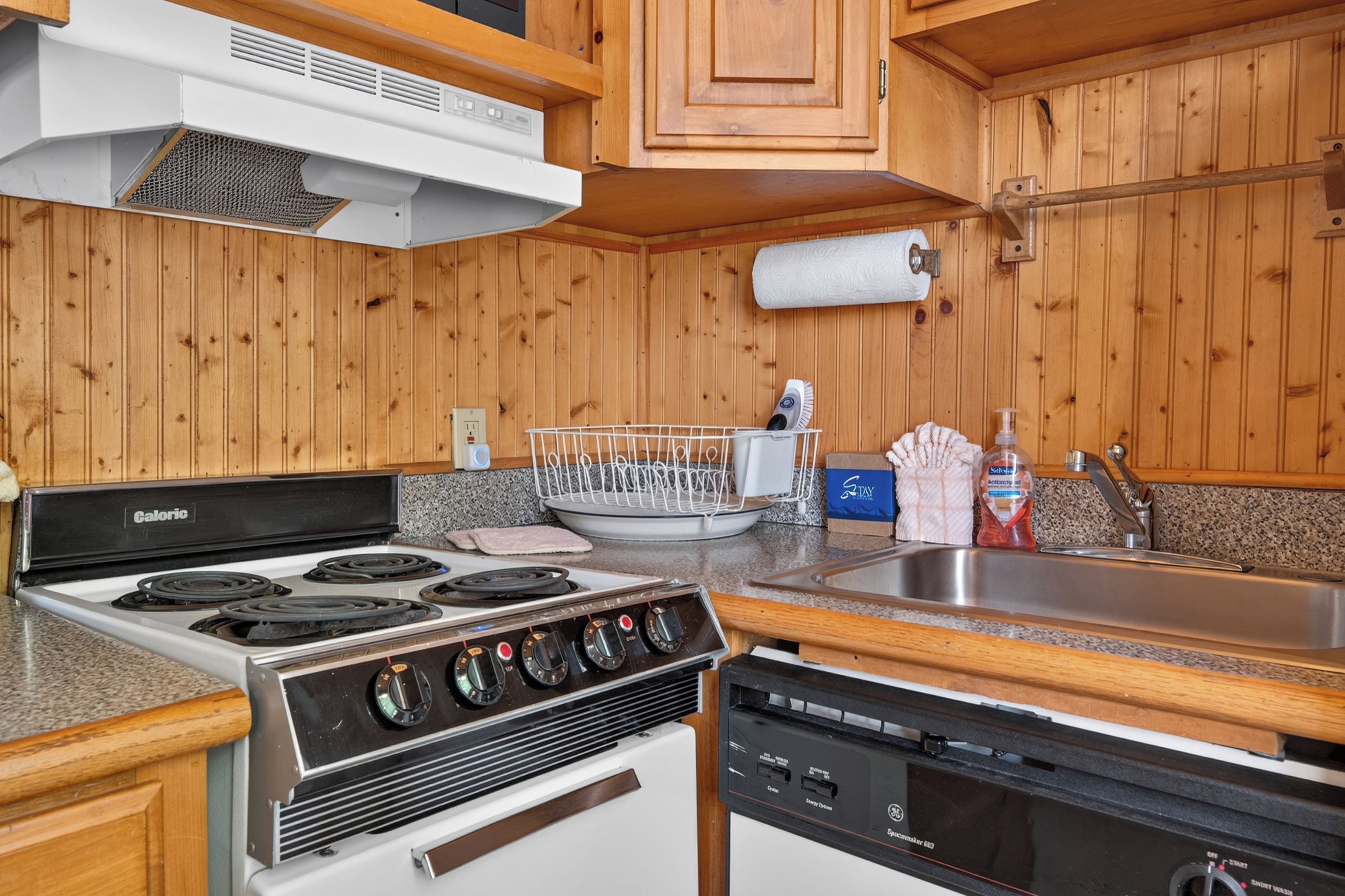 A kitchen with a stove, dishwasher, and wooden cabinets.