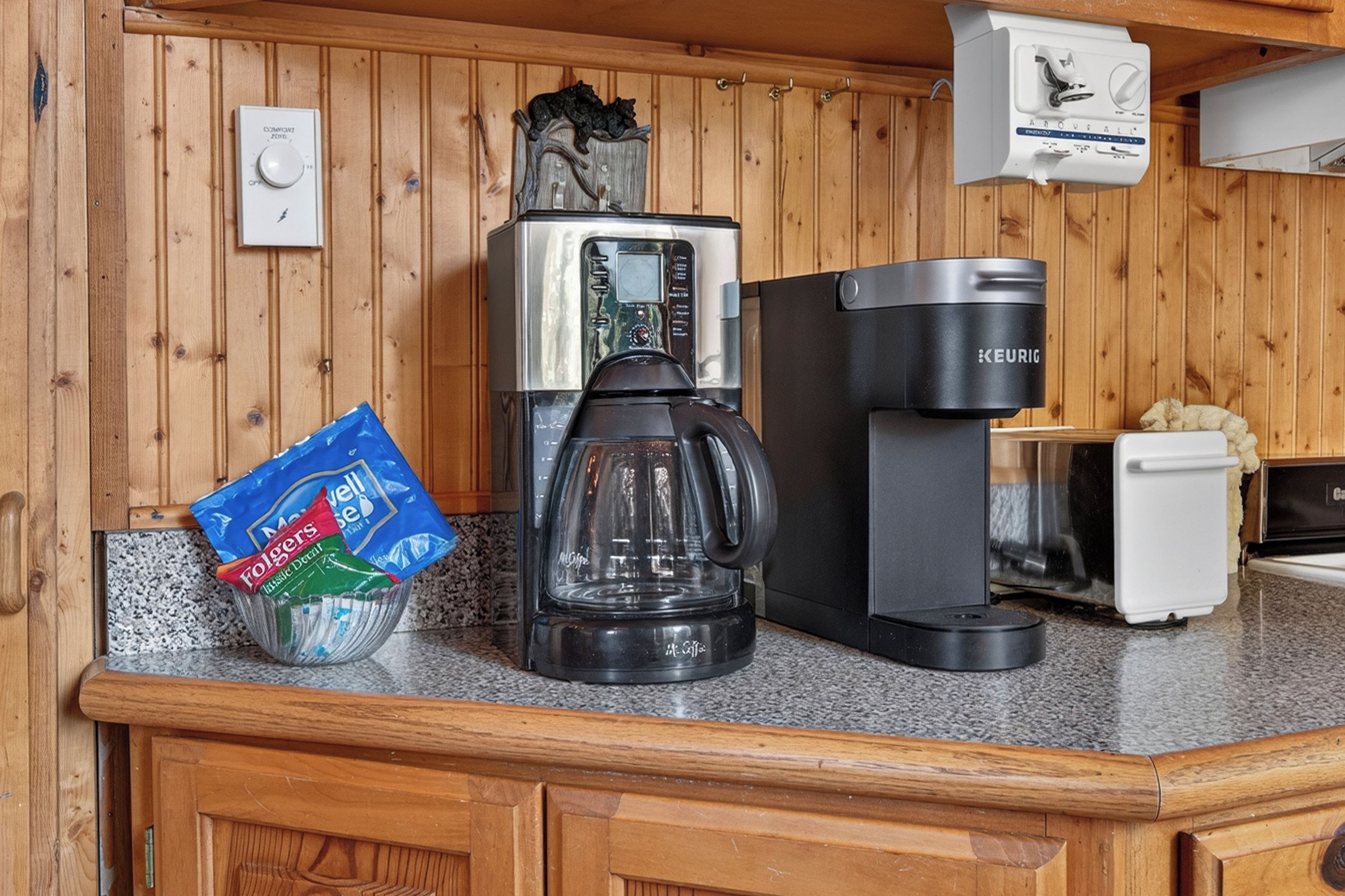 Eine Küchenarbeitsplatte mit Kaffeemaschine, Wasserkocher und einer Packung Kaffee-Kapseln.
