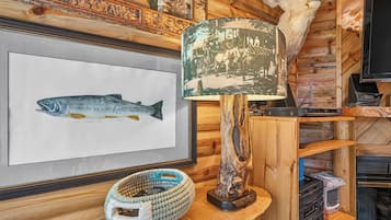A framed fish illustration, a woven basket, a lamp, and a television on a wooden wall.