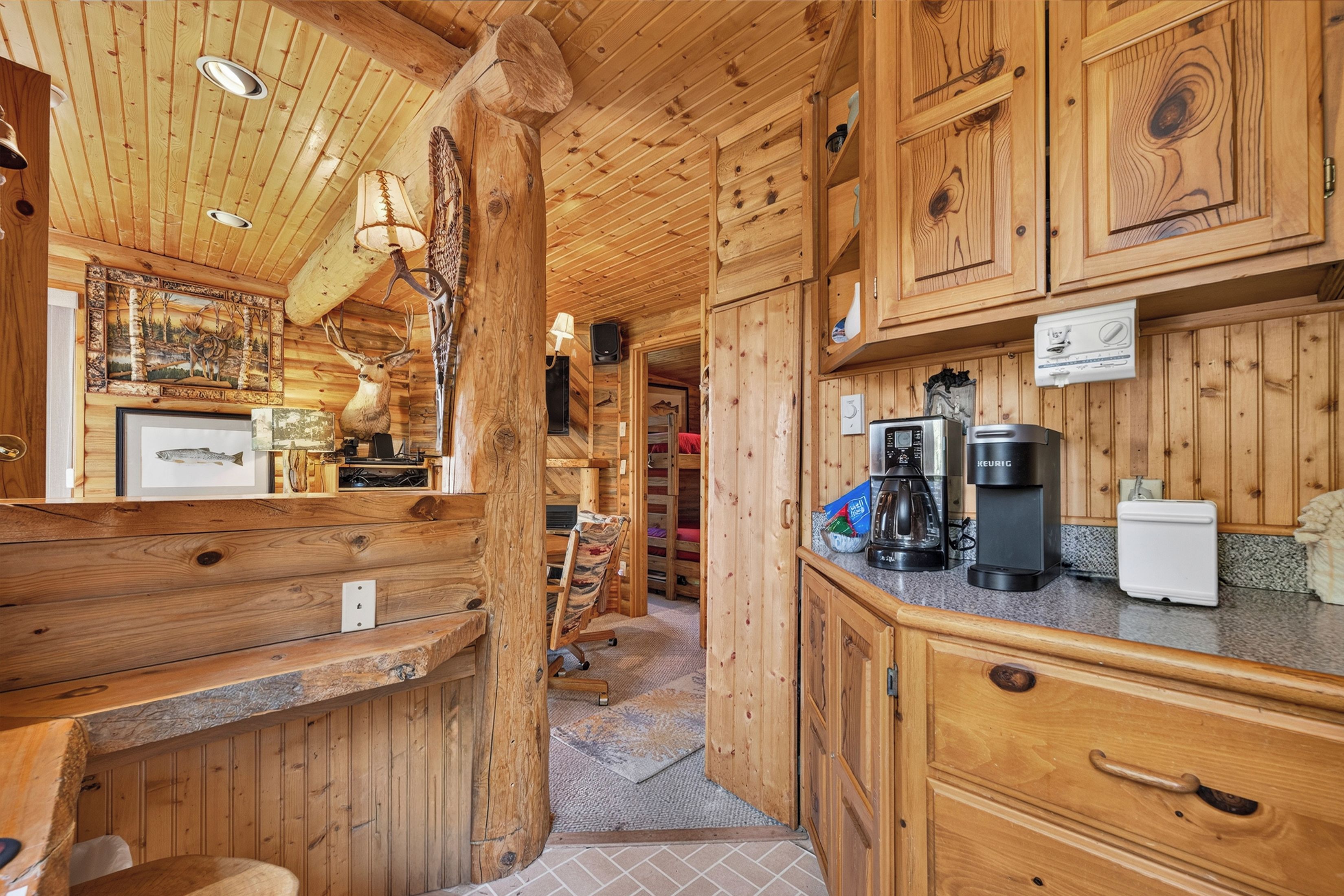 Interior de una cabaña de madera con cocina, una mesa de comedor y una chimenea.