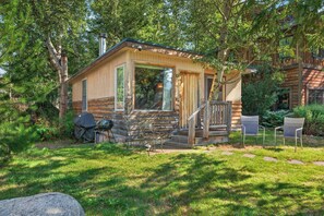 Eine Blockhütte mit Veranda, Grill und Stuhl.